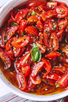 a white bowl filled with sliced tomatoes and herbs