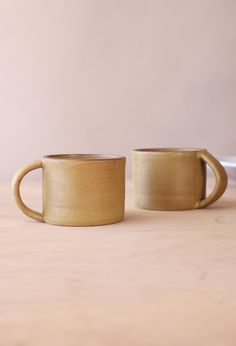 two coffee mugs sitting on top of a wooden table