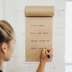 a woman writing on a piece of paper with a marker in front of her face