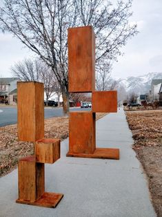 an art piece on the sidewalk in front of a tree with no leaves or branches