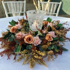 an arrangement of flowers and greenery on a white table cloth at a wedding reception