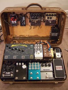 an old suitcase with many different types of pedals and amps in it on the floor