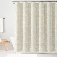 a white bath tub sitting next to a shower curtain with a floral pattern on it