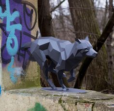 a paper sculpture of a wolf on top of a cement wall with graffiti in the background