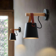 two lamps are hanging on the wall next to each other, one is black and one is brown