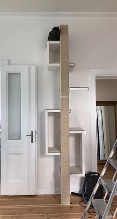 a ladder is in the middle of a room with white walls and wood flooring