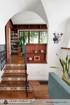 an entry way with stairs leading up to the second floor and bookshelves on either side