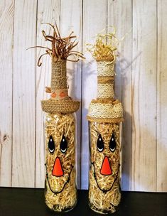 two glass bottles decorated with straw and painted faces