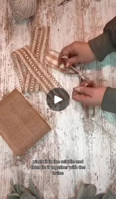 someone is cutting fabric with scissors on a wooden table next to yarn and other items