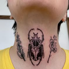 a woman with a scar on her neck has a beetle tattoo on it's neck