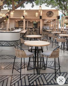 an outdoor dining area with tables and chairs under a tree in front of a bar