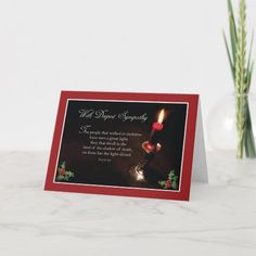 a christmas card with a lit candle on it next to a vase filled with flowers