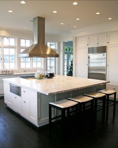 a large kitchen with an island in the middle and three stools at the end