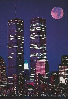 two tall skyscrapers in the city at night with a full moon behind them and buildings lit up