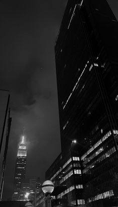 black and white photograph of skyscrapers at night with street lights in the foreground