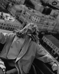 a woman sitting on top of a building next to a cityscape with buildings in the background