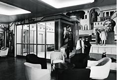 an old black and white photo of people in a room with art on the walls