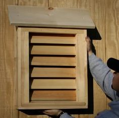 a person holding up a wooden box with shutters