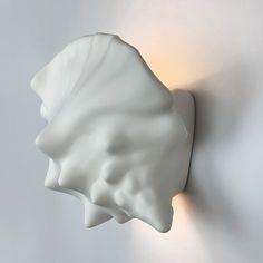 a white wall light mounted to the side of a wall