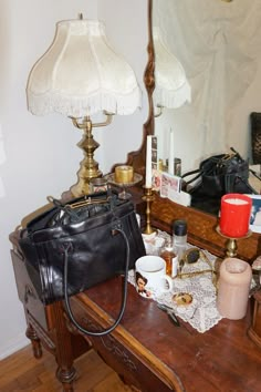 a purse sitting on top of a wooden table next to a lamp and mirror in a room