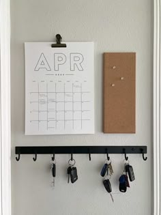 a calendar hanging on a wall with keys attached to it and a clipboard next to it