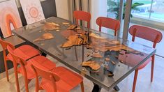 a glass table with orange chairs around it