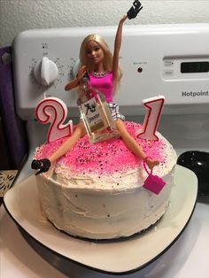 a barbie doll sitting on top of a birthday cake with pink sprinkles