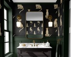 a bathroom with green walls and white counter tops, along with a gold framed mirror on the wall