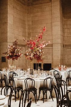 the tables are set with white tablecloths and tall vases filled with flowers