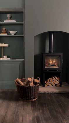 a basket sitting on the floor next to a fire place in a room with green walls