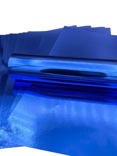 several pieces of shiny blue paper are stacked on top of each other in front of a white background