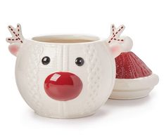 a white cup with a red nose and antlers on it next to a bowl