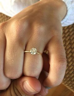 a close up of a person's hand with a diamond ring on their finger