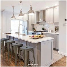 a kitchen with an island and four stools in front of the countertop area