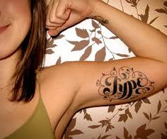 a woman with a tattoo on her arm that says love and is pointing to the side