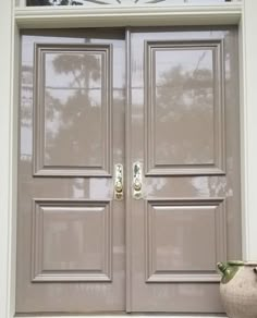 the front door is painted gray and has two handles on each side, along with a potted plant next to it