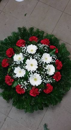 red and white flowers are arranged in a circular arrangement on the ground with greenery