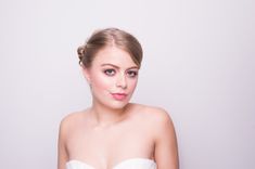 a woman in a strapless white dress poses for the camera with her hands on her hips