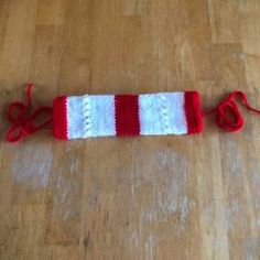 a red and white knitted object laying on the floor