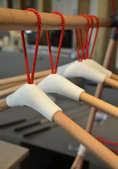 three wooden poles with white handles and red strings hanging from the ends, in front of a workbench