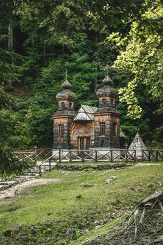 an old building in the middle of a forest with trees and grass on the ground