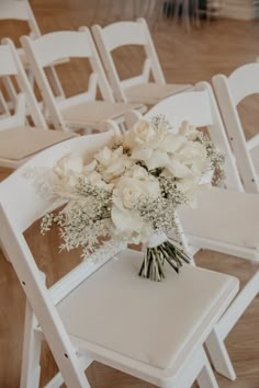 a bouquet of flowers sitting on top of a white chair in front of rows of chairs