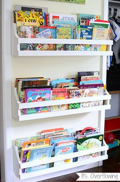 three white shelves filled with children's books on top of a hard wood floor