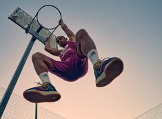 a man in purple shirt and shorts jumping up into the air with a tennis racket