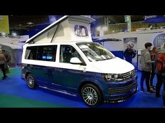 a white van parked on top of a blue floor next to people standing in front of it