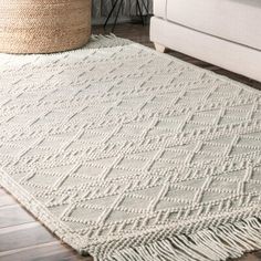 a white rug with fringes on the floor in front of a couch and chair