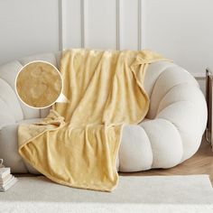 a couch covered in a yellow blanket next to a stack of books on the floor