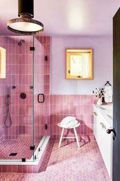 a bathroom with pink tiles on the walls and floor, along with a stand up shower