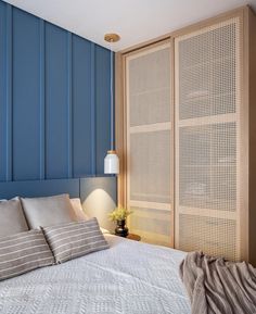 a bed sitting next to a blue wall with wooden slats on the headboard