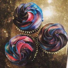 three cupcakes with colorful frosting on top of each other and stars in the background